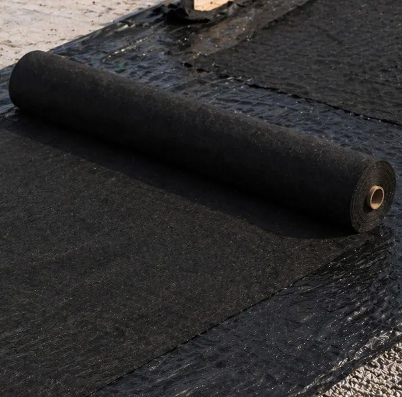 Roll of black building material being laid out on a roof.