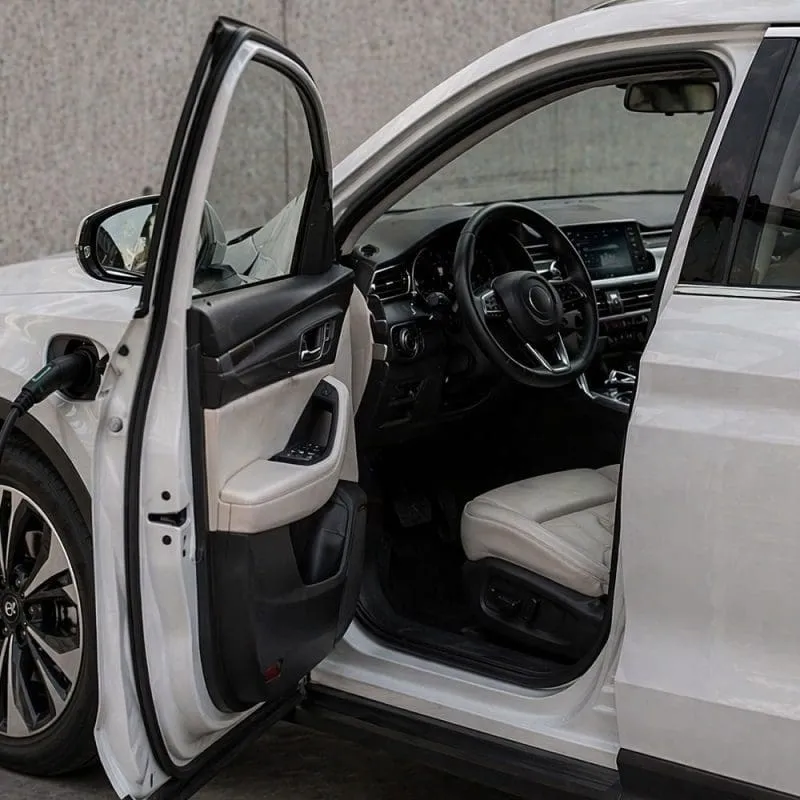Electric car charging with the driver’s door open, showing the interior.